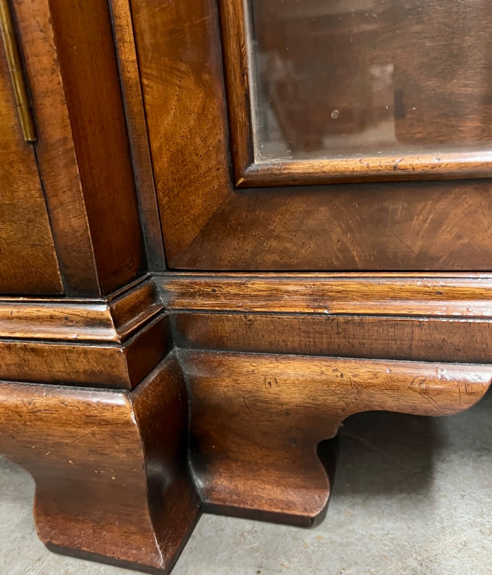 A low Queen Anne style walnut dwarf bookcase featuring a breakfront design with glazed side doors, a central veneered cupboard door, and bracket feet. View IV