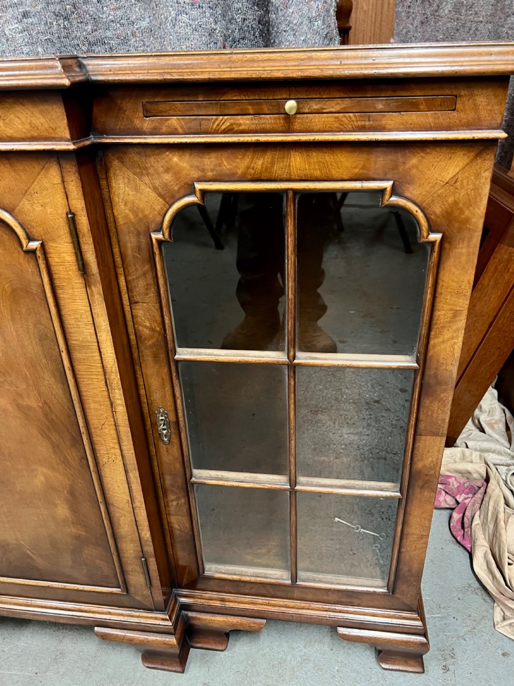 A low Queen Anne style walnut dwarf bookcase featuring a breakfront design with glazed side doors, a central veneered cupboard door, and bracket feet. View V