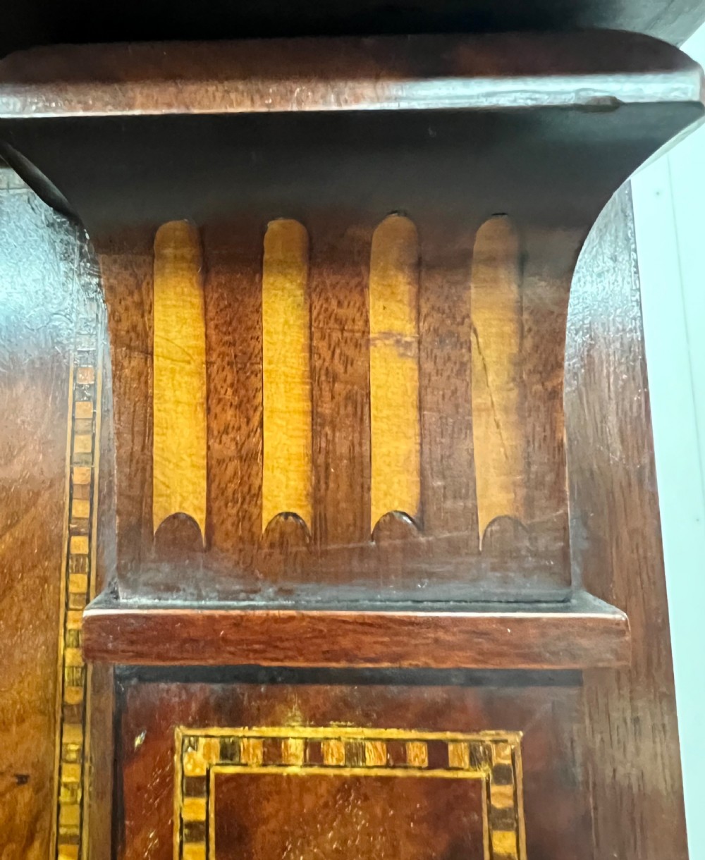An antique dark mahogany linen press featuring classical marquetry urn inlay, a broken pediment top, two cabinet doors, and four lower drawers with circular brass handles. View VII