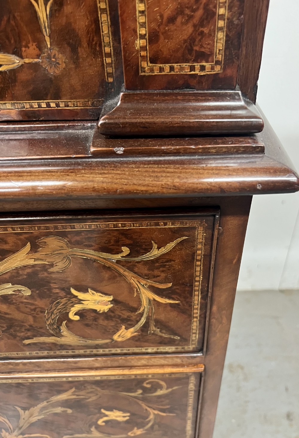 An antique dark mahogany linen press featuring classical marquetry urn inlay, a broken pediment top, two cabinet doors, and four lower drawers with circular brass handles. View VIII