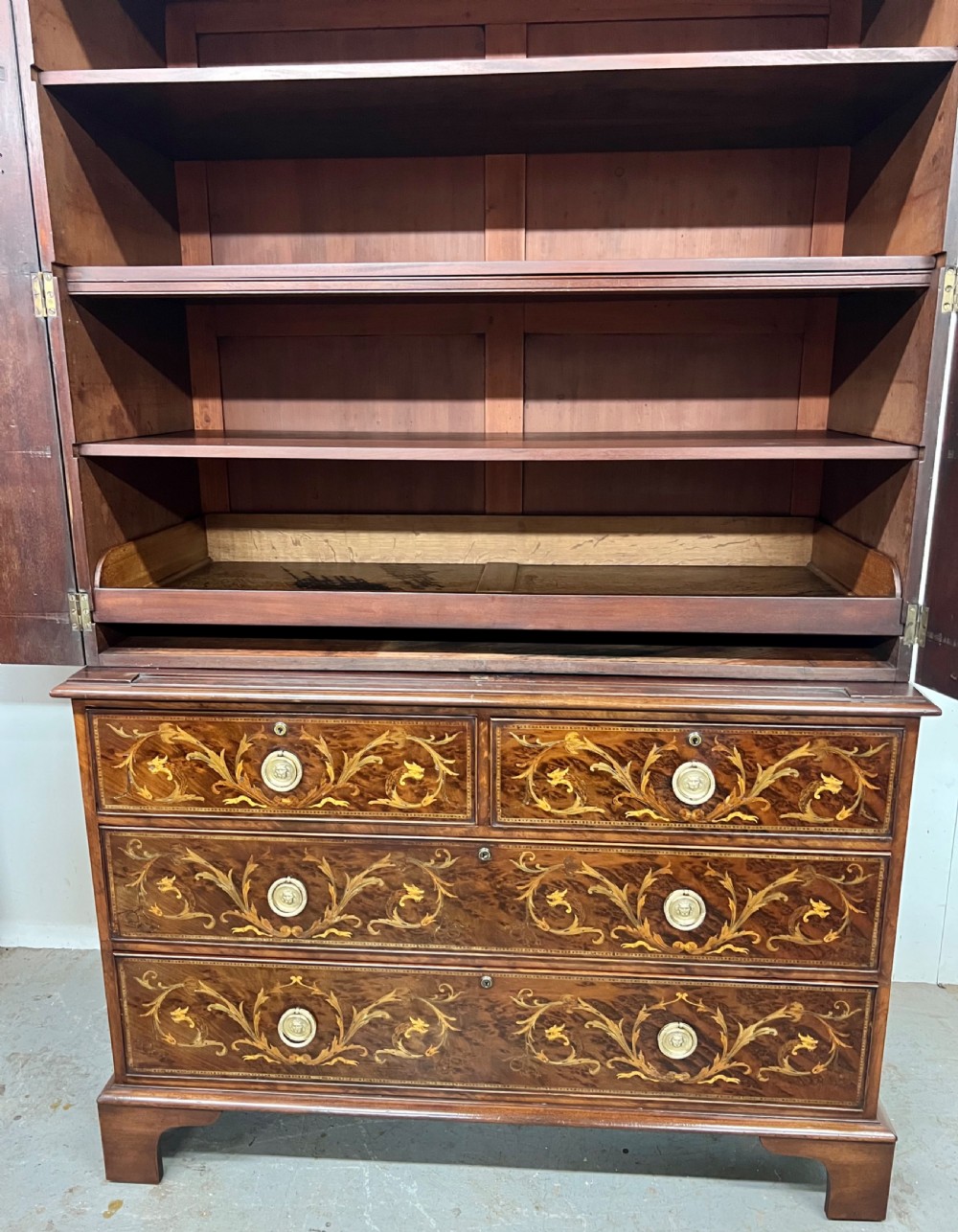 An antique dark mahogany linen press featuring classical marquetry urn inlay, a broken pediment top, two cabinet doors, and four lower drawers with circular brass handles. View XII