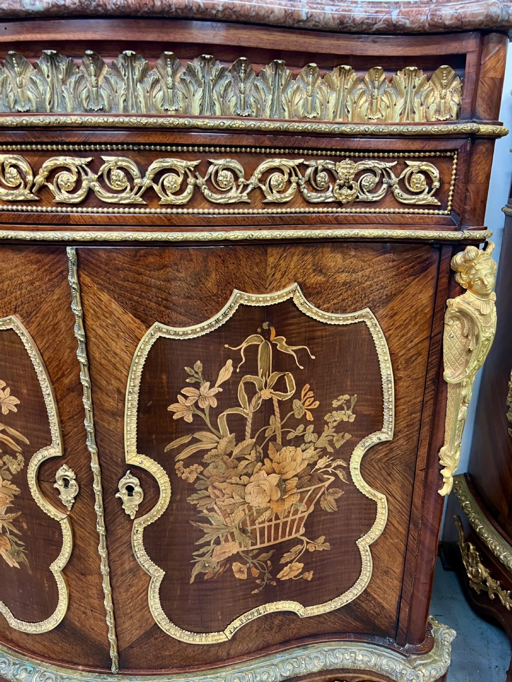 A pair of French Louis XV style kingwood side cabinets featuring floral marquetry, gilt-bronze ormolu mounts, and shaped pink marble tops. View VI