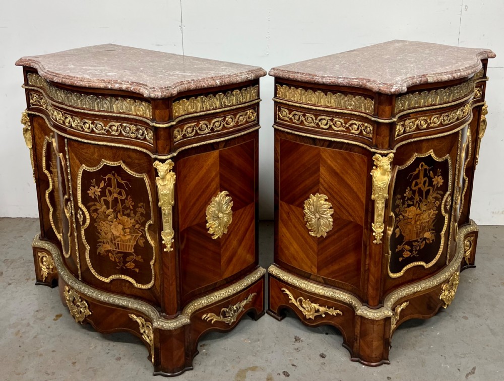 A pair of French Louis XV style kingwood side cabinets featuring floral marquetry, gilt-bronze ormolu mounts, and shaped pink marble tops. View XV