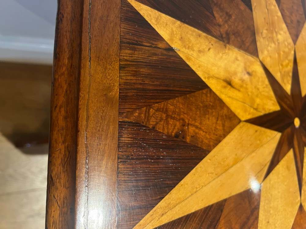 An octagonal antique specimen wood occasional table featuring a central geometric starburst marquetry top supported by a turned pedestal stem and tripod scroll feet. View VI