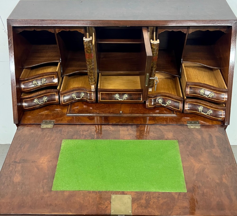 A Dutch burr walnut bureau with a slant-front writing slope, three contoured drawers, ornate brass handles, and carved claw and ball feet. View III