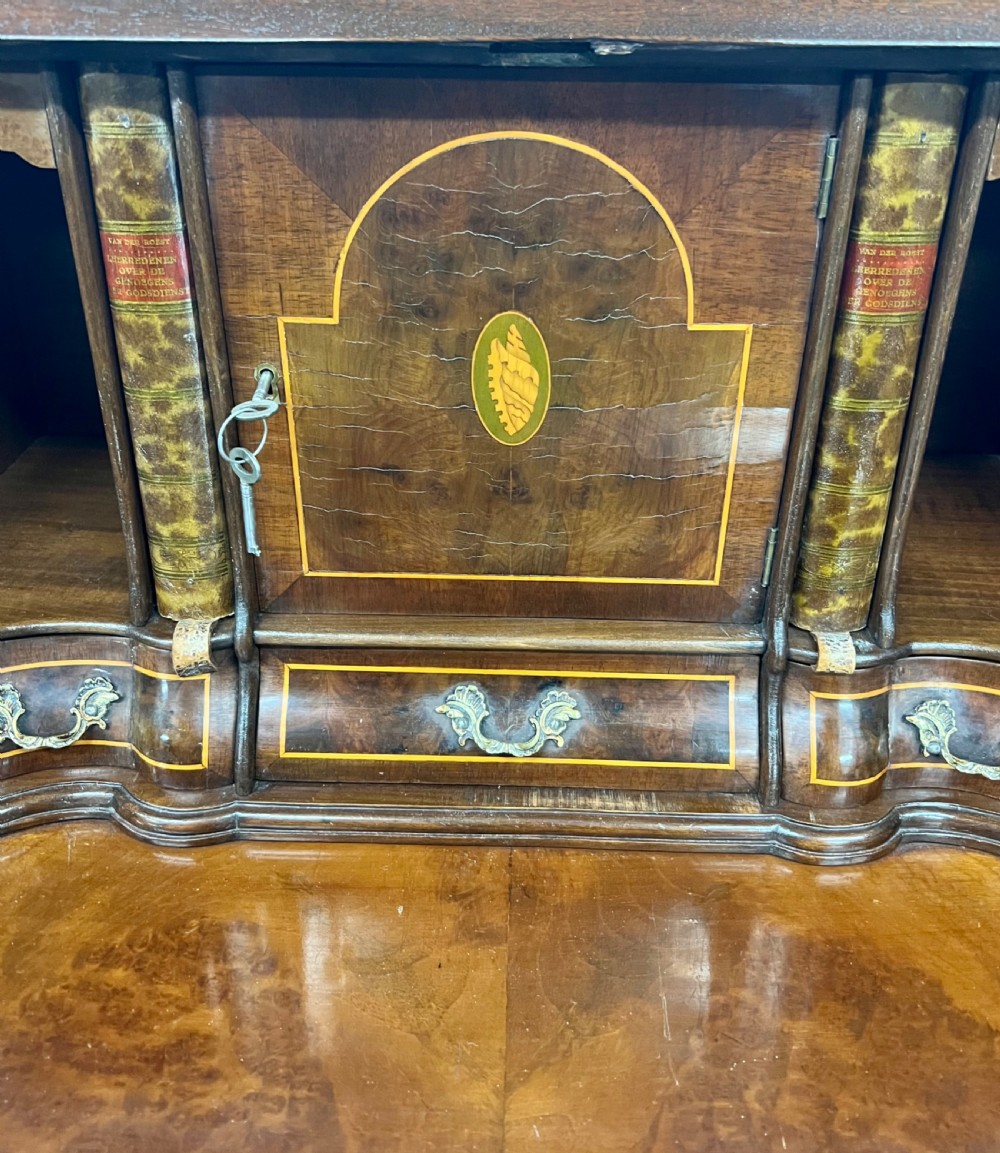 A Dutch burr walnut bureau with a slant-front writing slope, three contoured drawers, ornate brass handles, and carved claw and ball feet. View IV