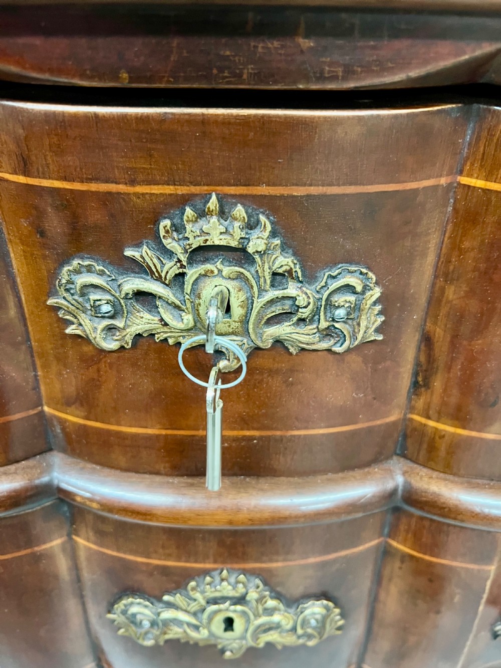 A Dutch burr walnut bureau with a slant-front writing slope, three contoured drawers, ornate brass handles, and carved claw and ball feet. View VII