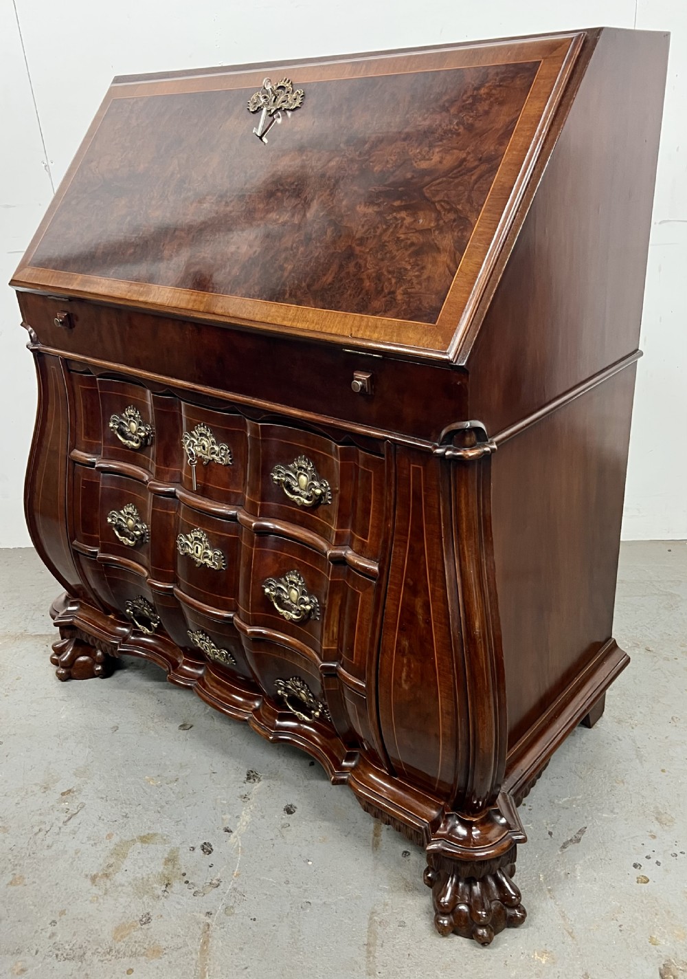 A Dutch burr walnut bureau with a slant-front writing slope, three contoured drawers, ornate brass handles, and carved claw and ball feet. View VIII