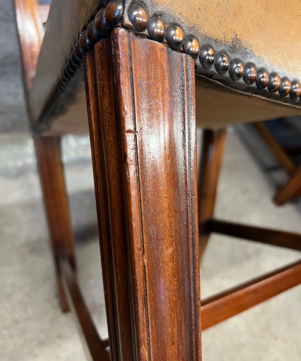 A set of eight Chippendale style mahogany dining chairs featuring serpentine ladderback splats and tan leather drop-in seats, including six side chairs and two carver armchairs. View VII