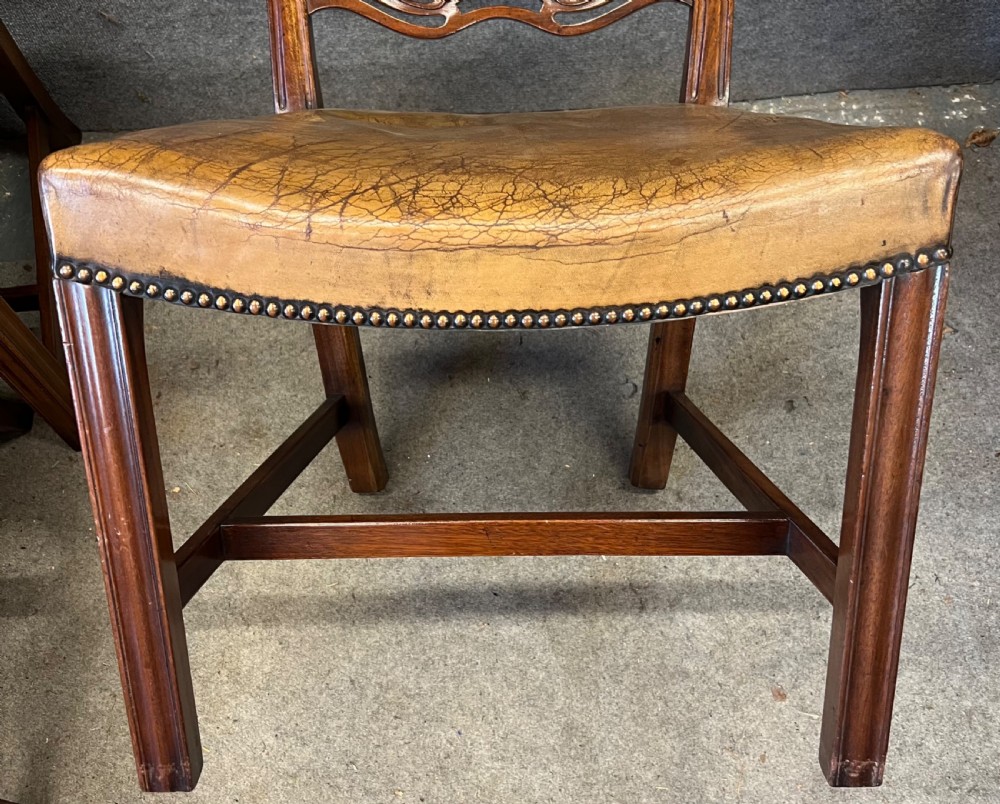 A set of eight Chippendale style mahogany dining chairs featuring serpentine ladderback splats and tan leather drop-in seats, including six side chairs and two carver armchairs. View VIII
