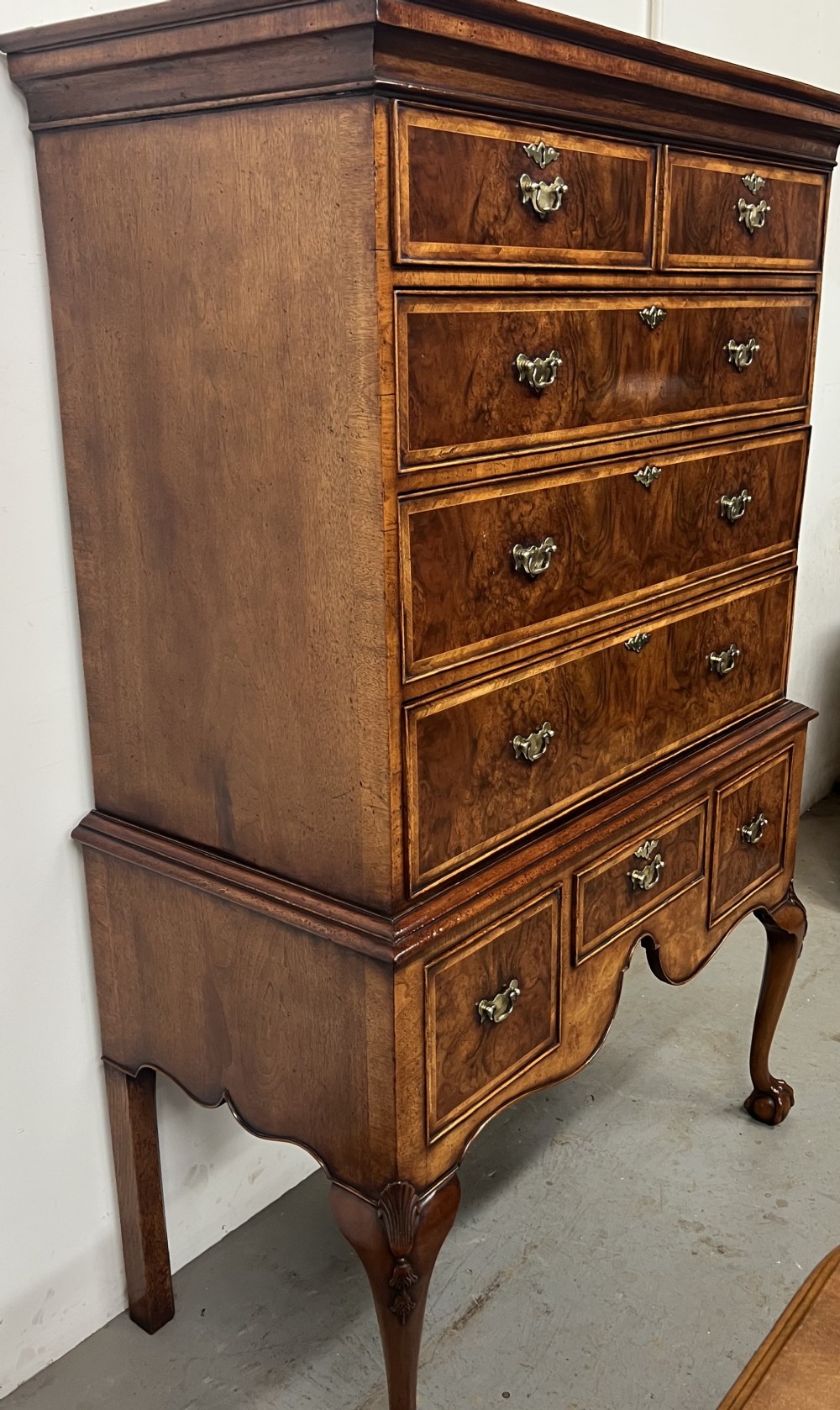 A tall burr walnut chest on stand featuring two short over three long drawers on top, three lower drawers, a shaped apron, and carved cabriole legs. View VI