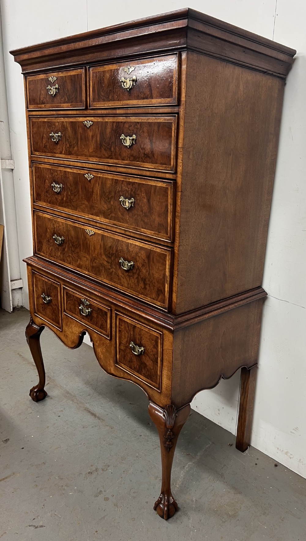 A tall burr walnut chest on stand featuring two short over three long drawers on top, three lower drawers, a shaped apron, and carved cabriole legs. View VII