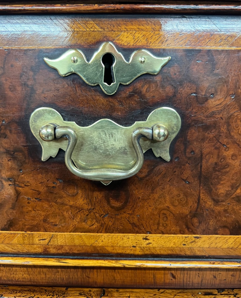 A tall burr walnut chest on stand featuring two short over three long drawers on top, three lower drawers, a shaped apron, and carved cabriole legs. View VIII