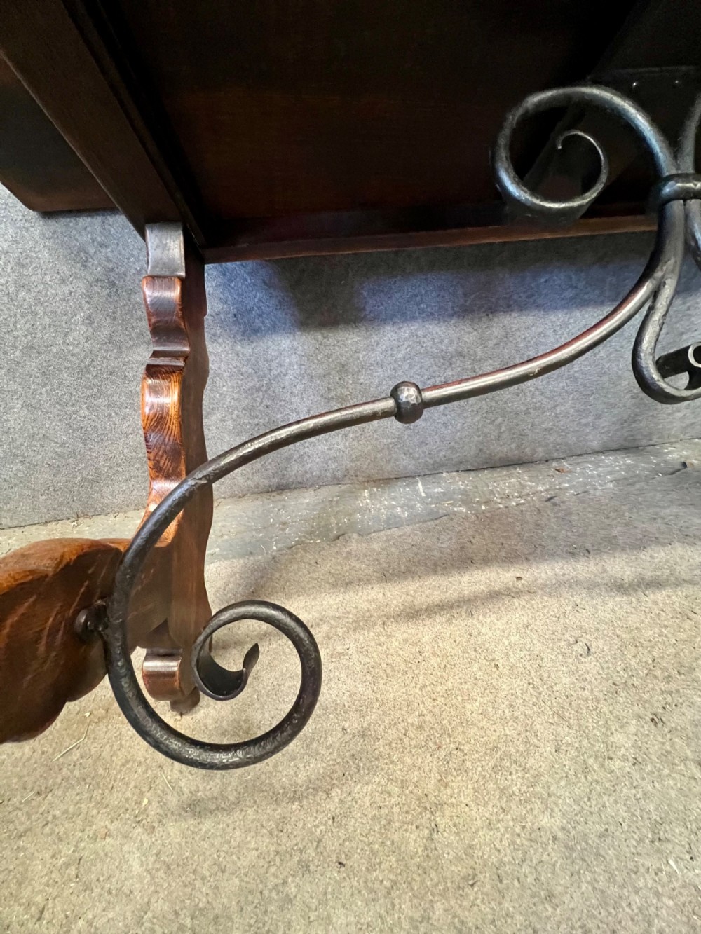 A dark oak Spanish console table featuring two carved drawers, lyre-shaped trestle legs, and a scrolled wrought iron stretcher. View VII