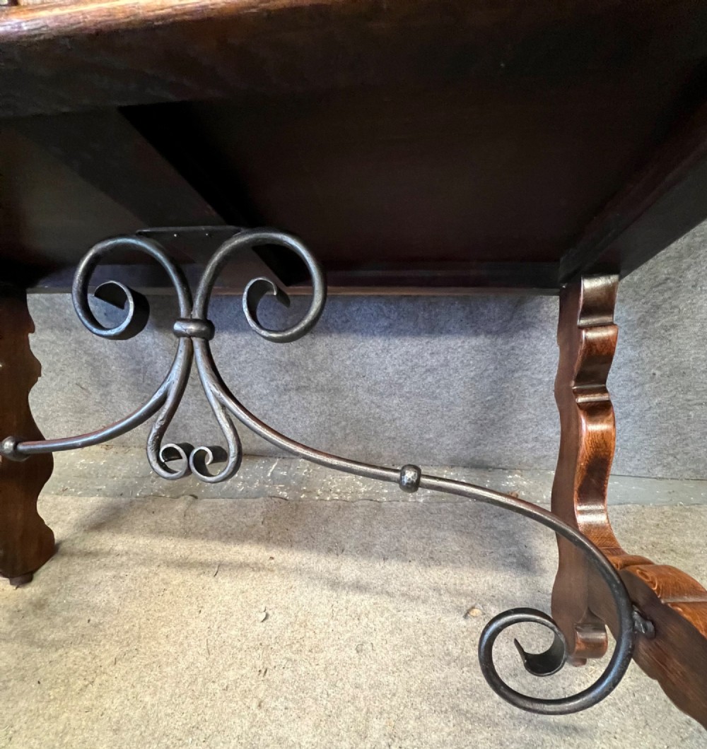 A dark oak Spanish console table featuring two carved drawers, lyre-shaped trestle legs, and a scrolled wrought iron stretcher. View VIII
