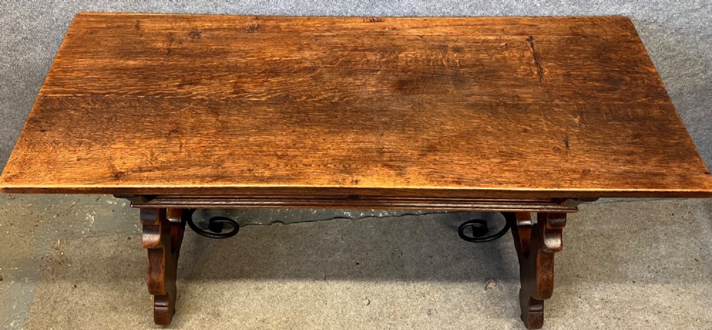A dark oak Spanish console table featuring two carved drawers, lyre-shaped trestle legs, and a scrolled wrought iron stretcher. View IX