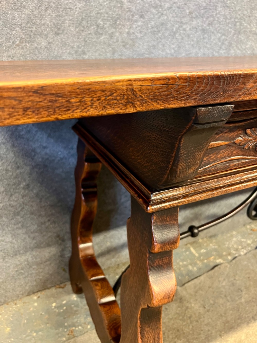 A dark oak Spanish console table featuring two carved drawers, lyre-shaped trestle legs, and a scrolled wrought iron stretcher. View XIV