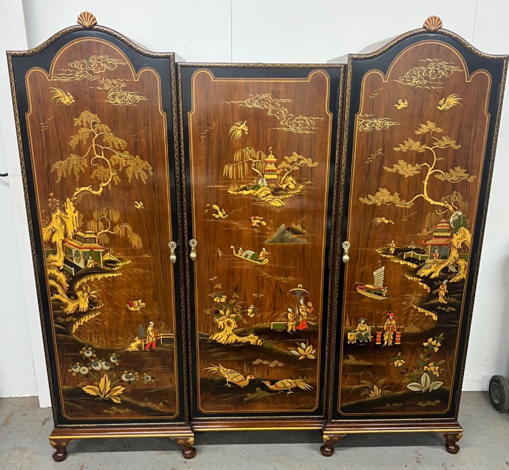 A multi-piece lacquered timber Chinoiserie bedroom suite by Maples and Co, featuring a dressing table with a triple mirror, wardrobes with gilt landscape scenes, and pink velvet upholstered stools. View II