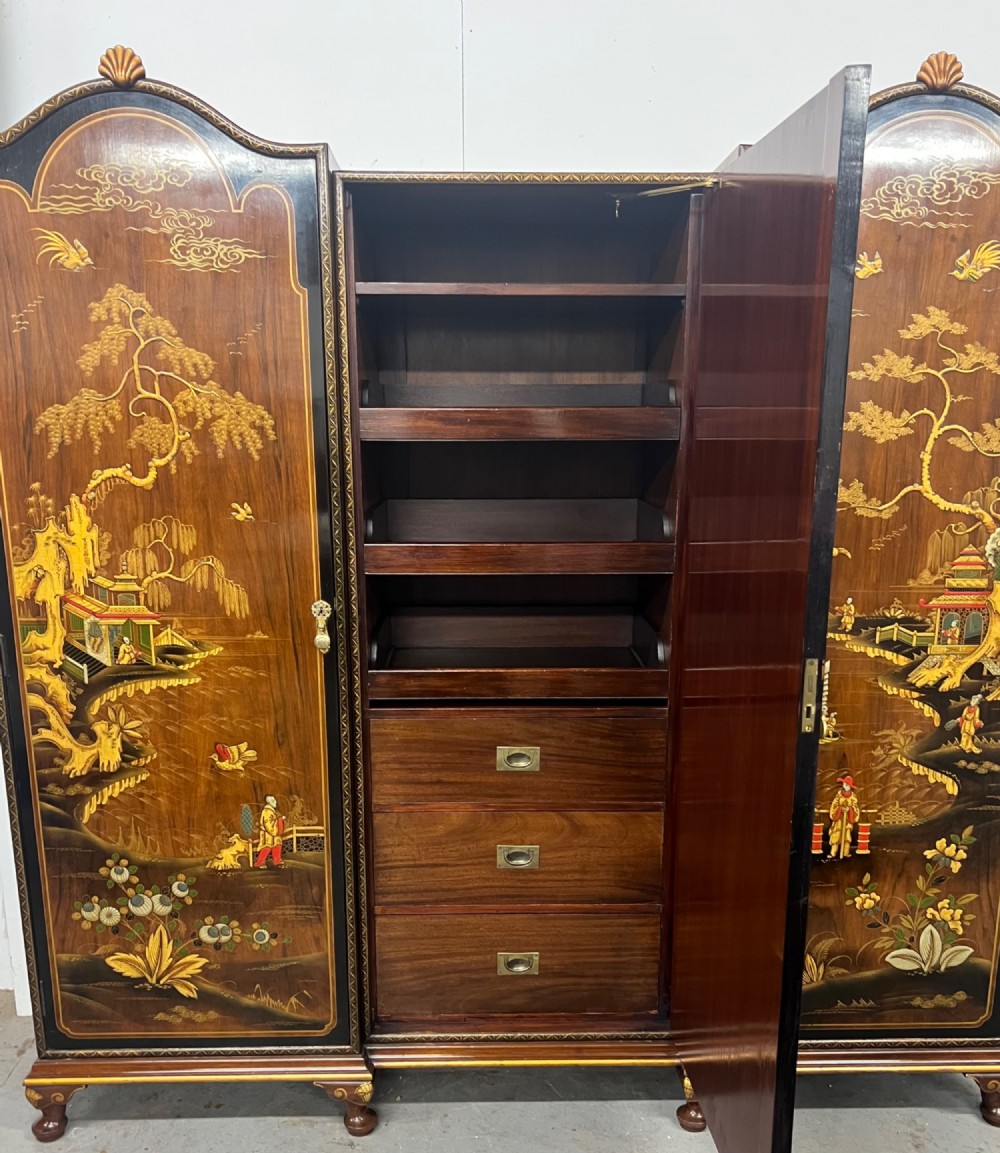 A multi-piece lacquered timber Chinoiserie bedroom suite by Maples and Co, featuring a dressing table with a triple mirror, wardrobes with gilt landscape scenes, and pink velvet upholstered stools. View III
