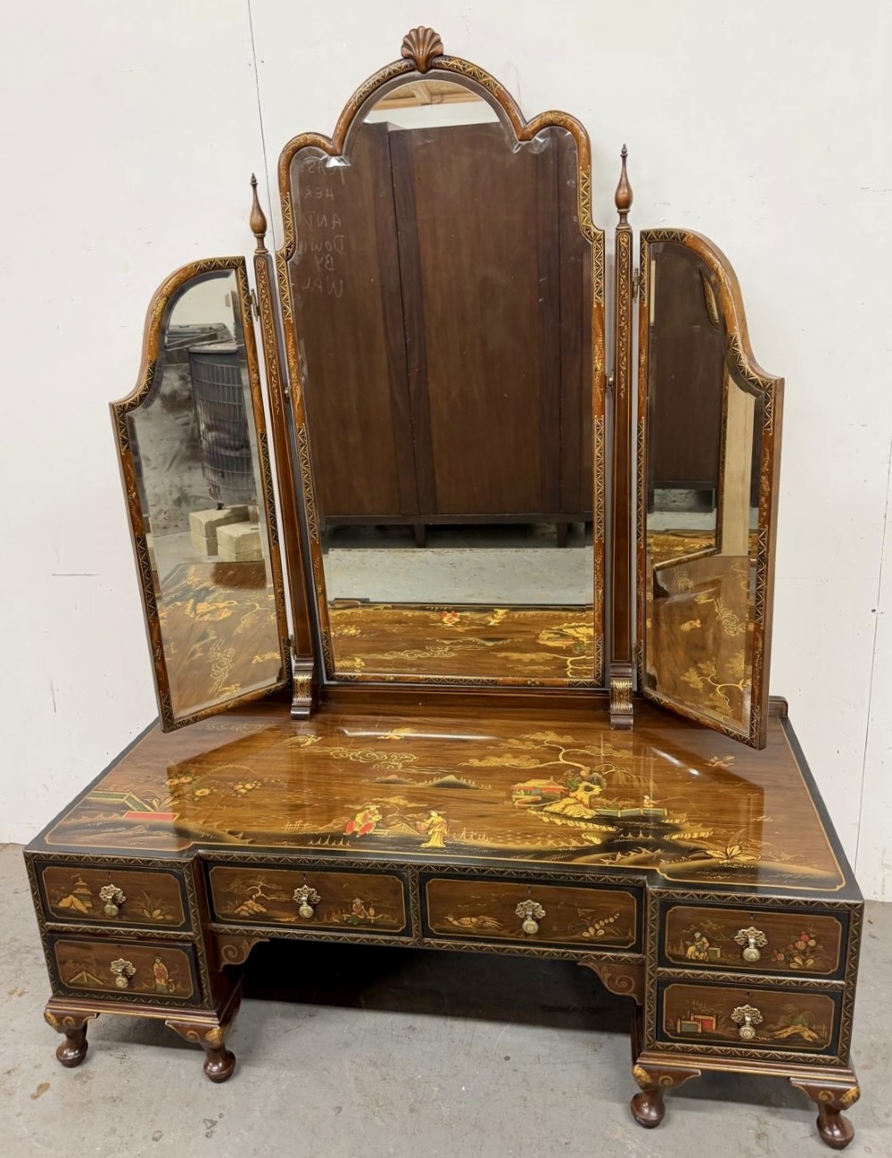 A multi-piece lacquered timber Chinoiserie bedroom suite by Maples and Co, featuring a dressing table with a triple mirror, wardrobes with gilt landscape scenes, and pink velvet upholstered stools. View V