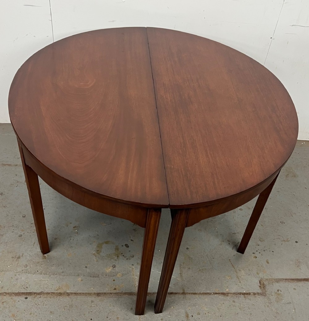 A pair of semi-circular George IV mahogany demilune console tables with polished surfaces and straight tapered legs. View II