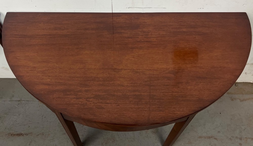 A pair of semi-circular George IV mahogany demilune console tables with polished surfaces and straight tapered legs. View IV