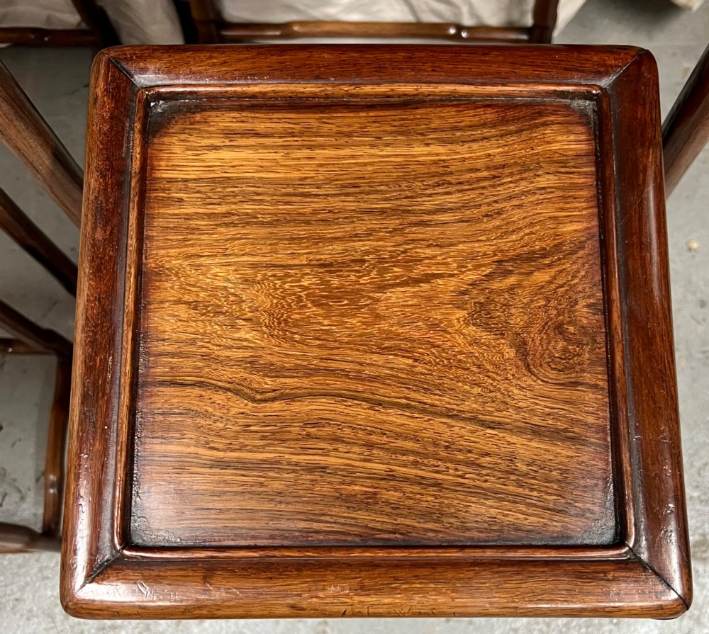 A set of four graduated brown Chinese hardwood nesting tables featuring carved scroll aprons and floating panel tops. View V