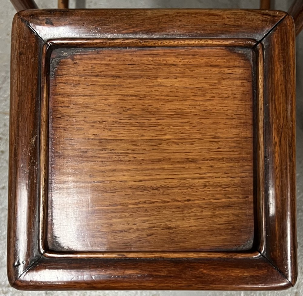 A set of four graduated brown Chinese hardwood nesting tables featuring carved scroll aprons and floating panel tops. View VI