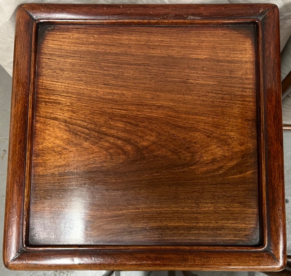 A set of four graduated brown Chinese hardwood nesting tables featuring carved scroll aprons and floating panel tops. View VII