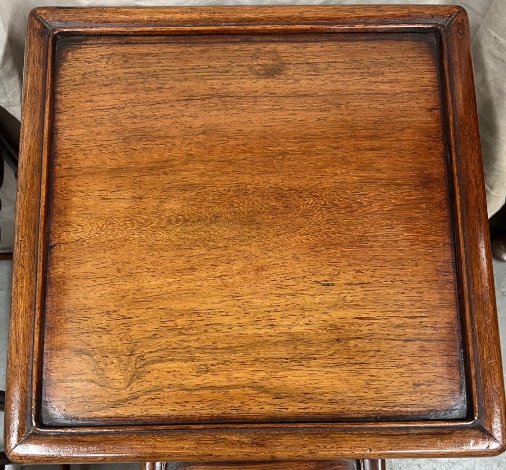 A set of four graduated brown Chinese hardwood nesting tables featuring carved scroll aprons and floating panel tops. View VIII