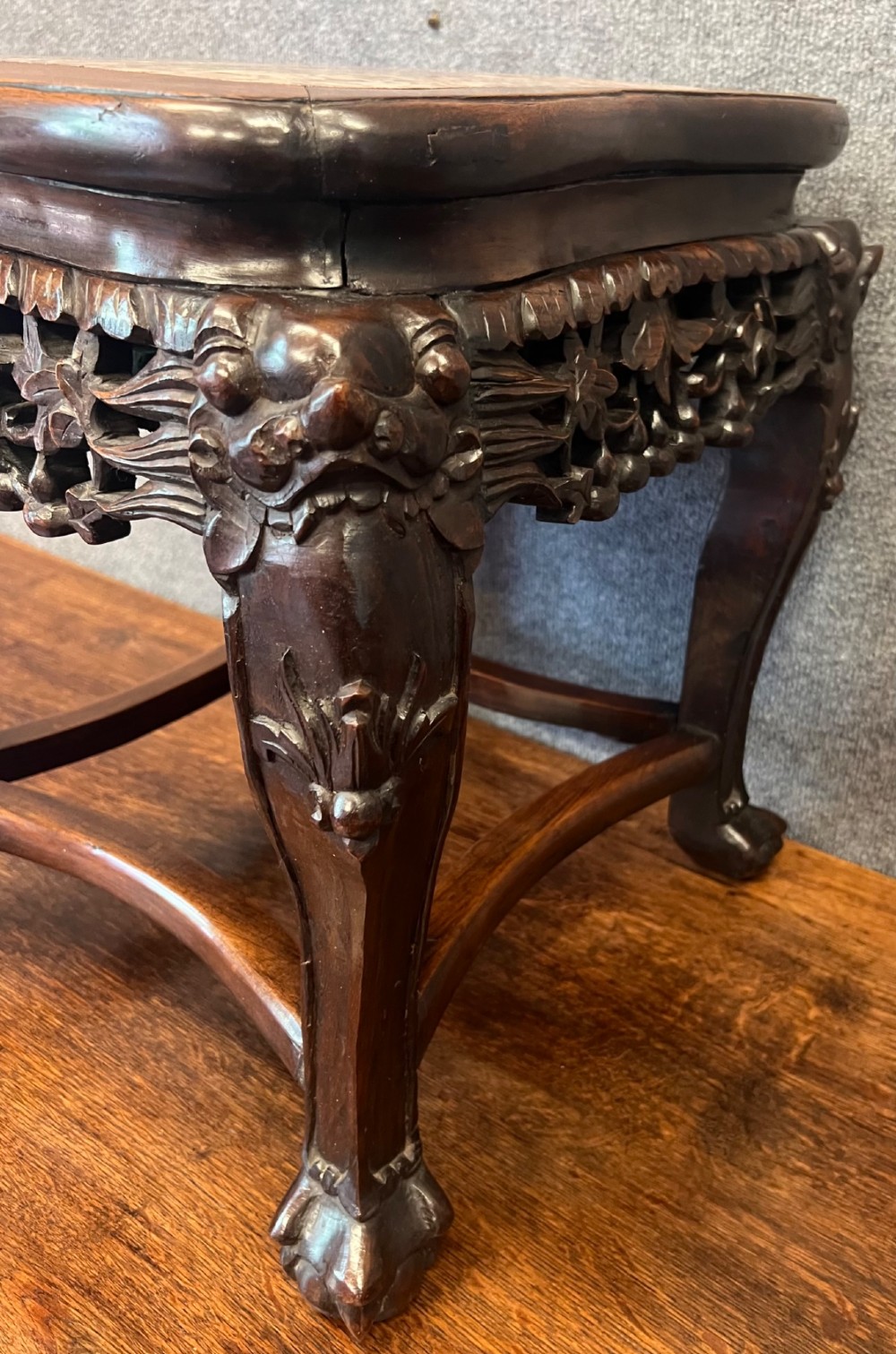 A dark carved Chinese hardwood stand featuring a pierced foliage apron, cabriole legs with mask details, and low stretchers. View IV
