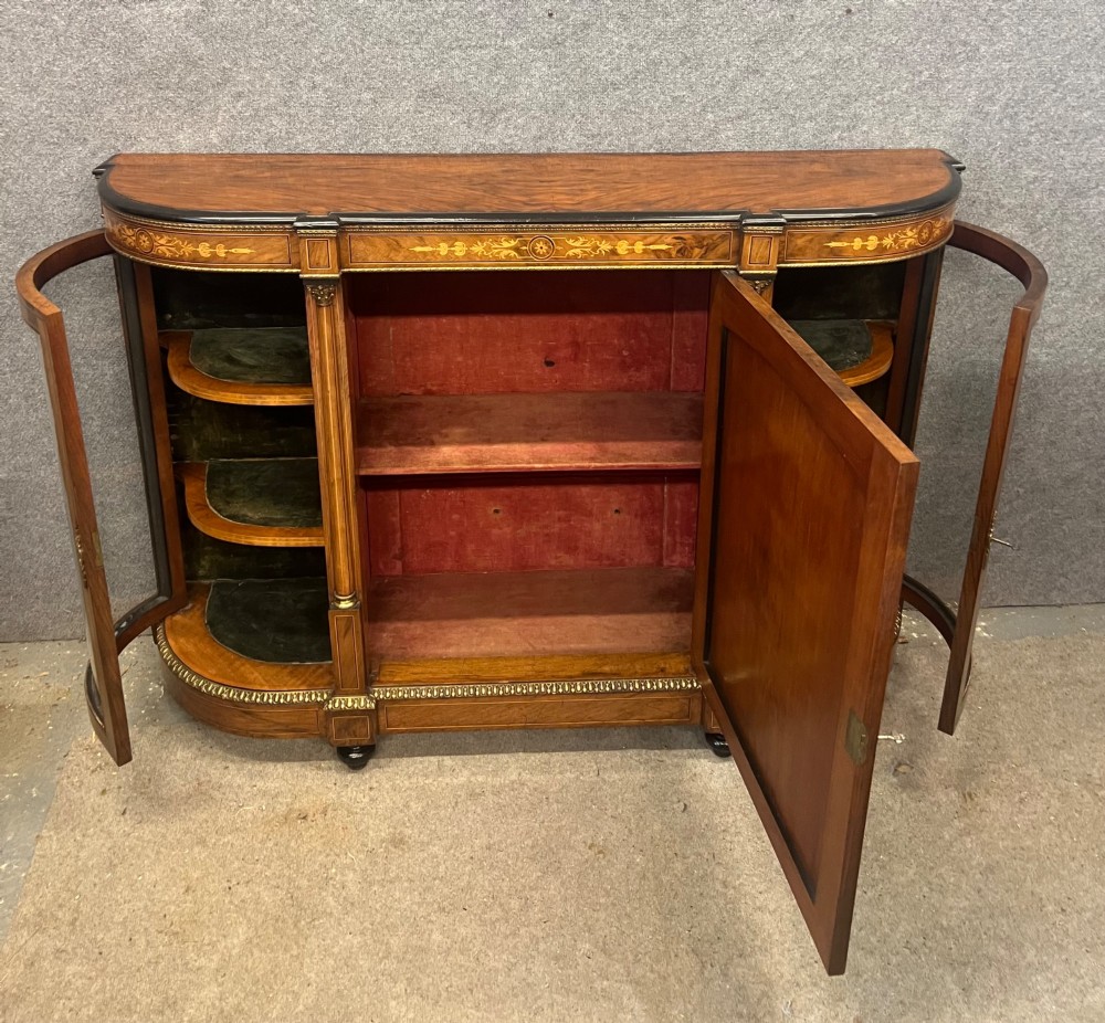 A Victorian credenza crafted from burr walnut with floral marquetry inlay, a central panelled cupboard door, curved glass display bays, and ornate ormolu mounts. View III