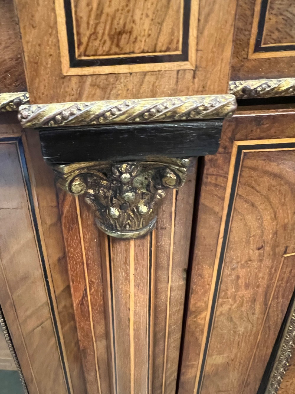 A Victorian credenza crafted from burr walnut with floral marquetry inlay, a central panelled cupboard door, curved glass display bays, and ornate ormolu mounts. View VIII