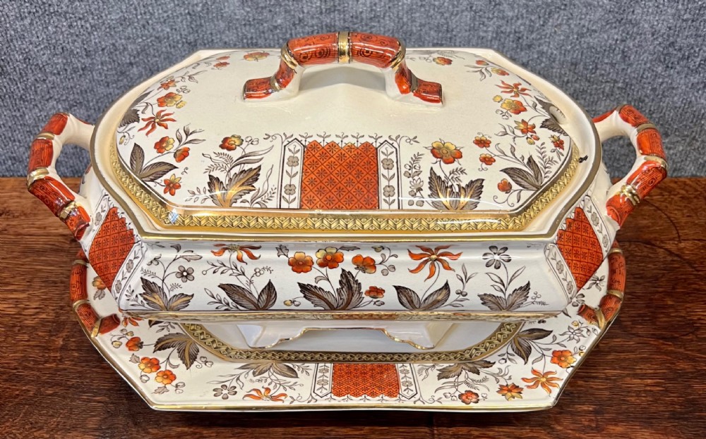 A fifty-nine piece Victorian earthenware dinner service decorated in rust orange, brown floral transfer patterns, and gilt accents arranged on a dark wood surface. View II