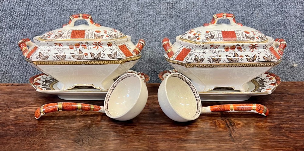 A fifty-nine piece Victorian earthenware dinner service decorated in rust orange, brown floral transfer patterns, and gilt accents arranged on a dark wood surface. View III