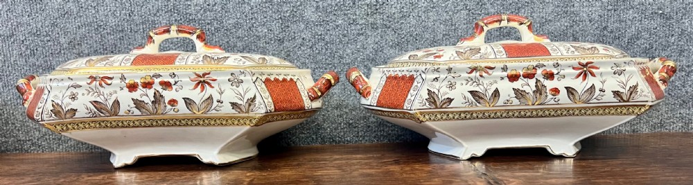 A fifty-nine piece Victorian earthenware dinner service decorated in rust orange, brown floral transfer patterns, and gilt accents arranged on a dark wood surface. View VI