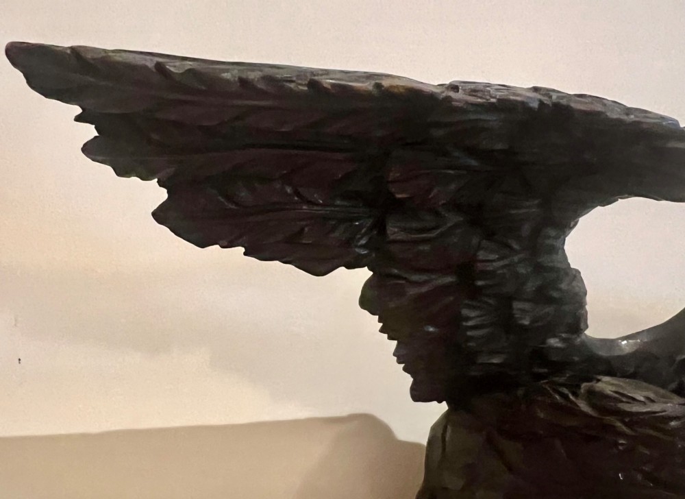 A dark stained oval wooden wall mirror featuring a carved eagle with spread wings perched atop a frame decorated with beaded and rope-twist detailing. View IV