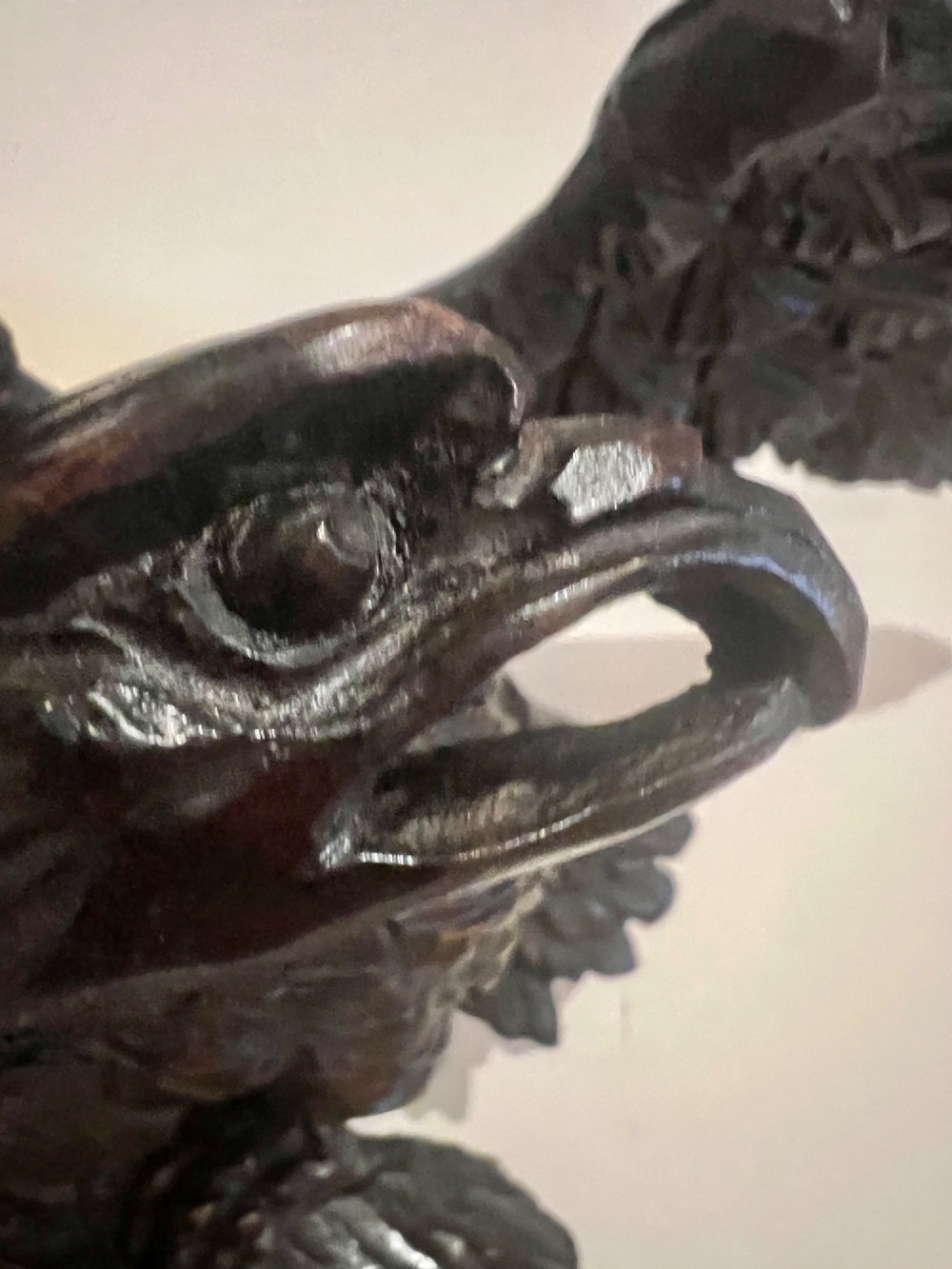 A dark stained oval wooden wall mirror featuring a carved eagle with spread wings perched atop a frame decorated with beaded and rope-twist detailing. View V