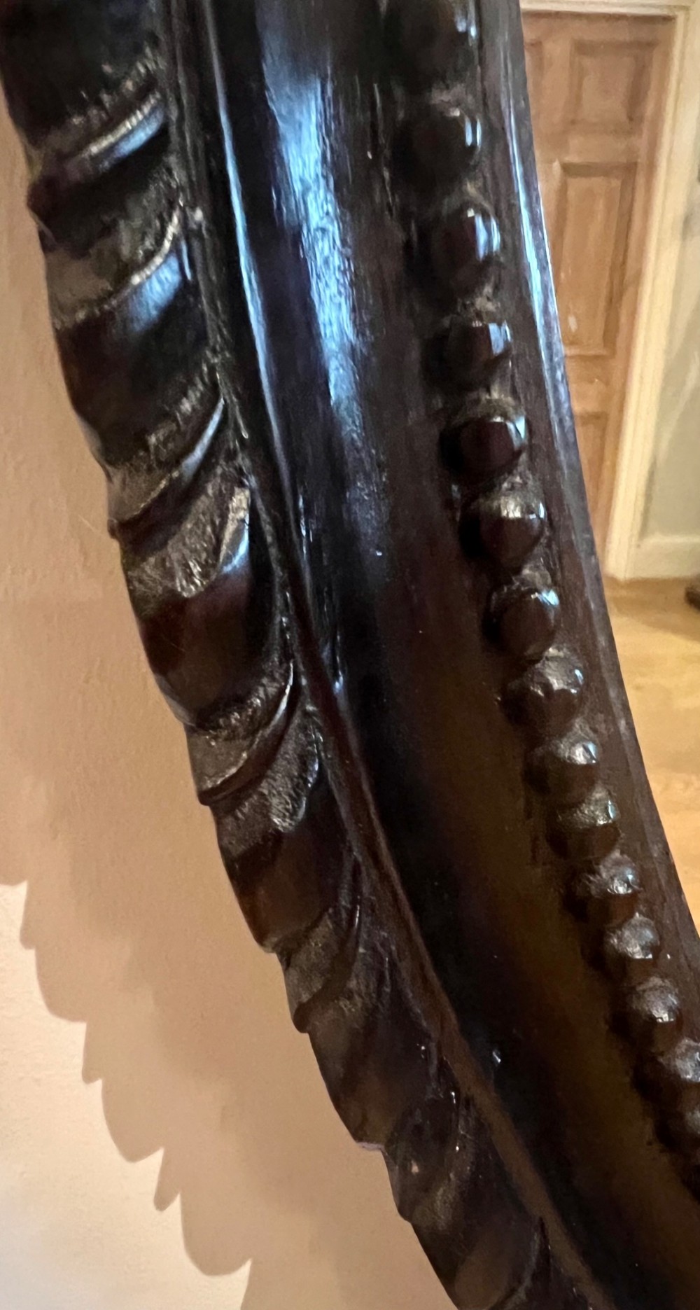 A dark stained oval wooden wall mirror featuring a carved eagle with spread wings perched atop a frame decorated with beaded and rope-twist detailing. View VI