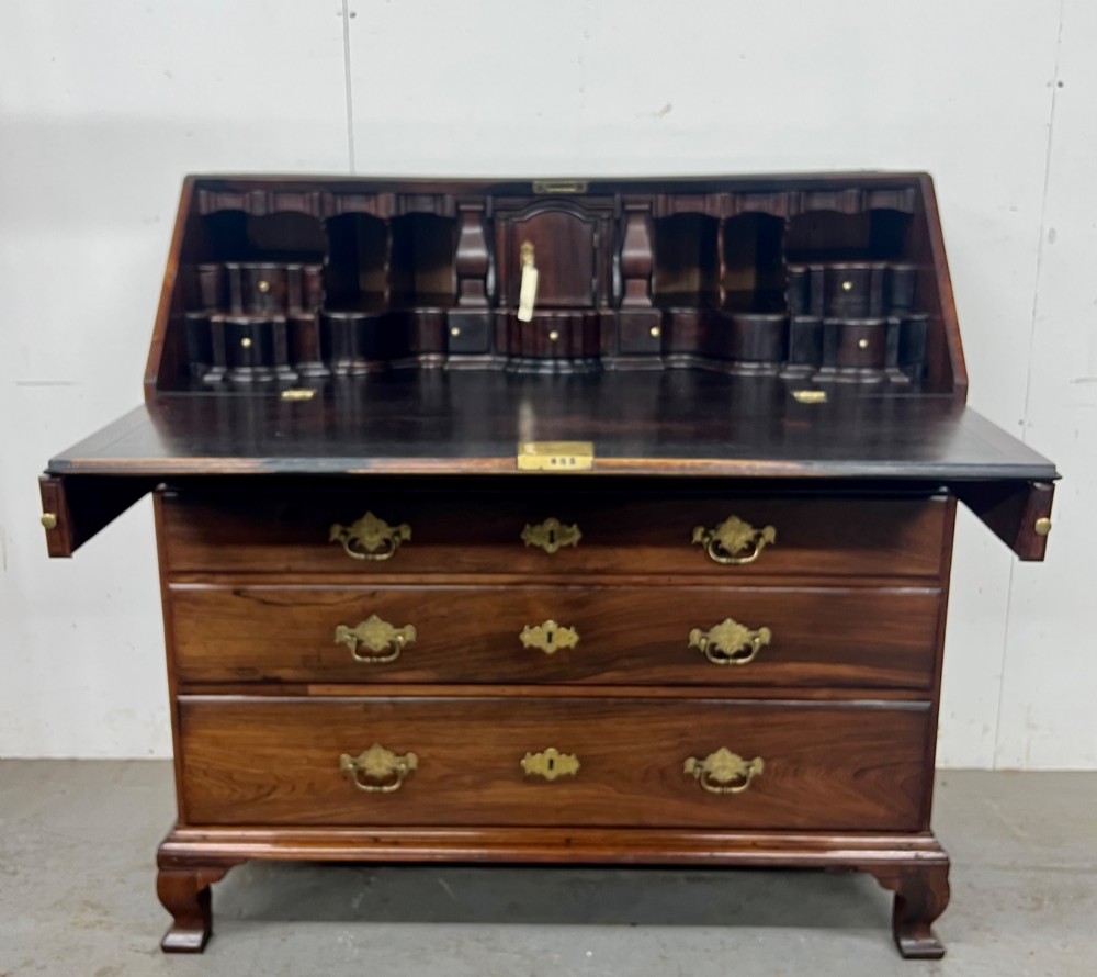An 18th-century dark rosewood slant-front bureau shown open, featuring a stepped fitted interior, brass drop handles, and three long drawers below.