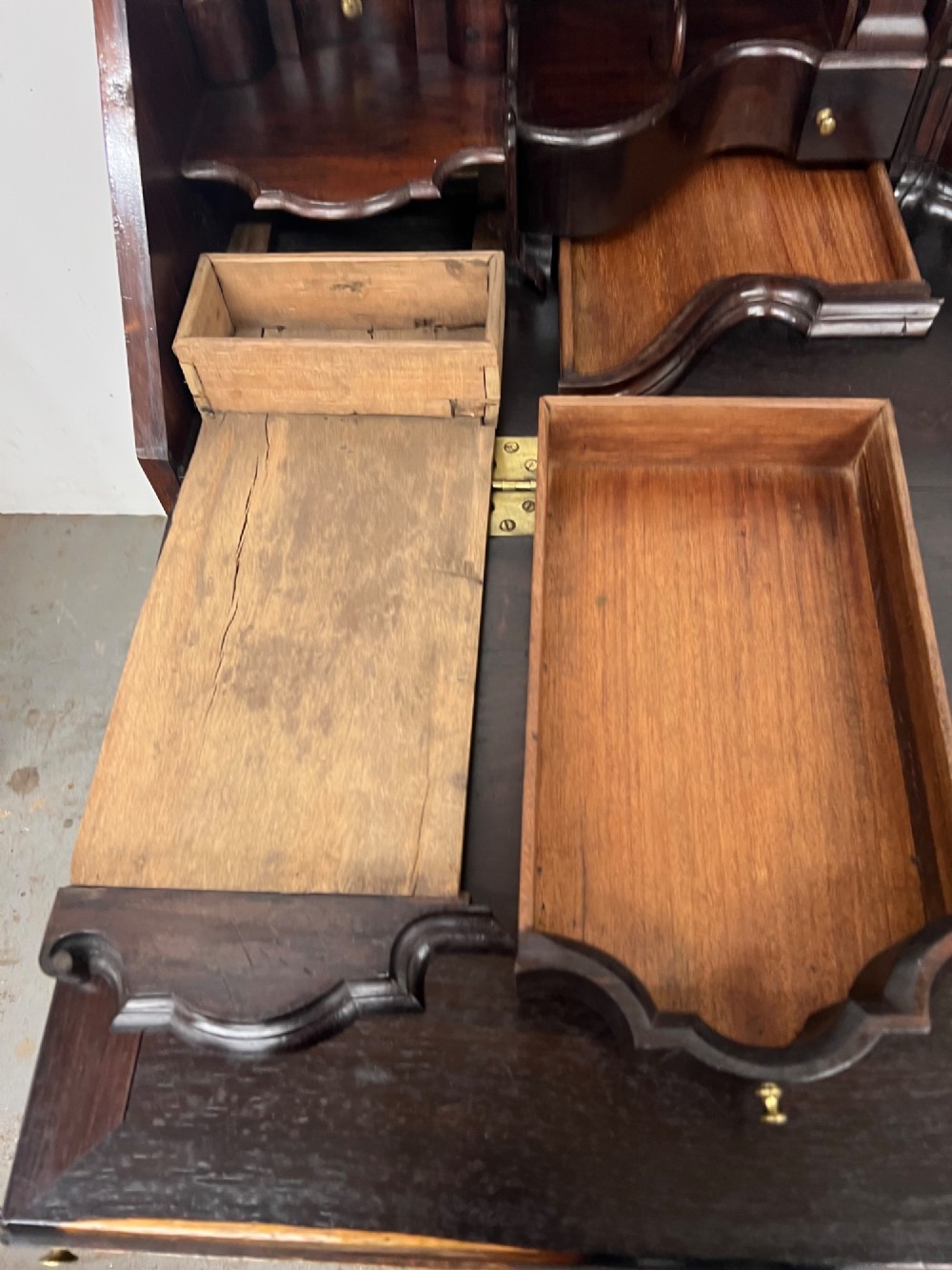 An 18th-century dark rosewood slant-front bureau shown open, featuring a stepped fitted interior, brass drop handles, and three long drawers below. View IX
