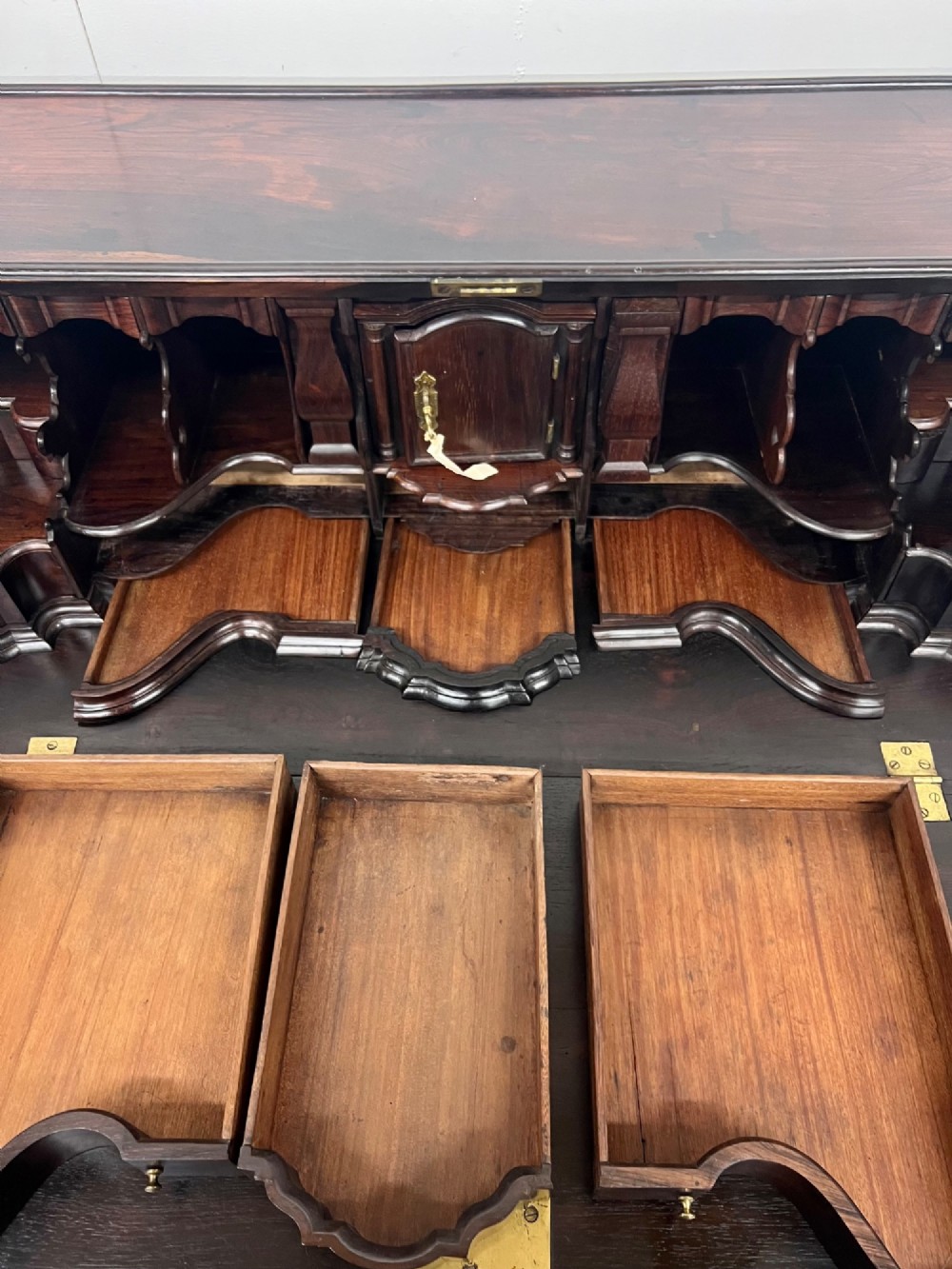 An 18th-century dark rosewood slant-front bureau shown open, featuring a stepped fitted interior, brass drop handles, and three long drawers below. View XII