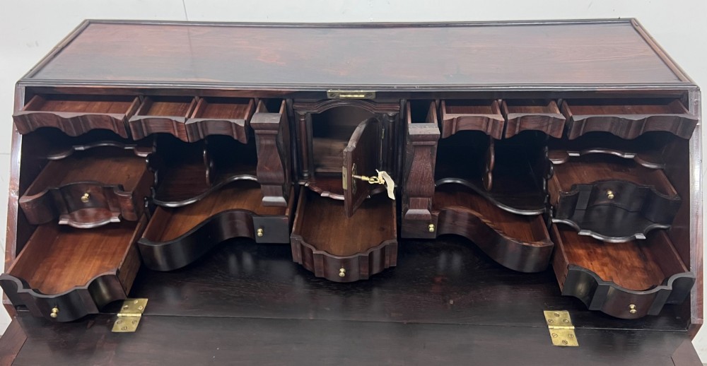 An 18th-century dark rosewood slant-front bureau shown open, featuring a stepped fitted interior, brass drop handles, and three long drawers below. View XIII