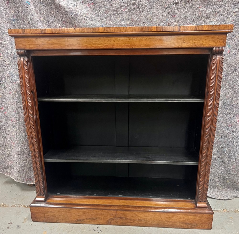 A low Regency open bookcase crafted from dark polished wood featuring carved twist mouldings on the side columns and three open shelves above a solid plinth base.