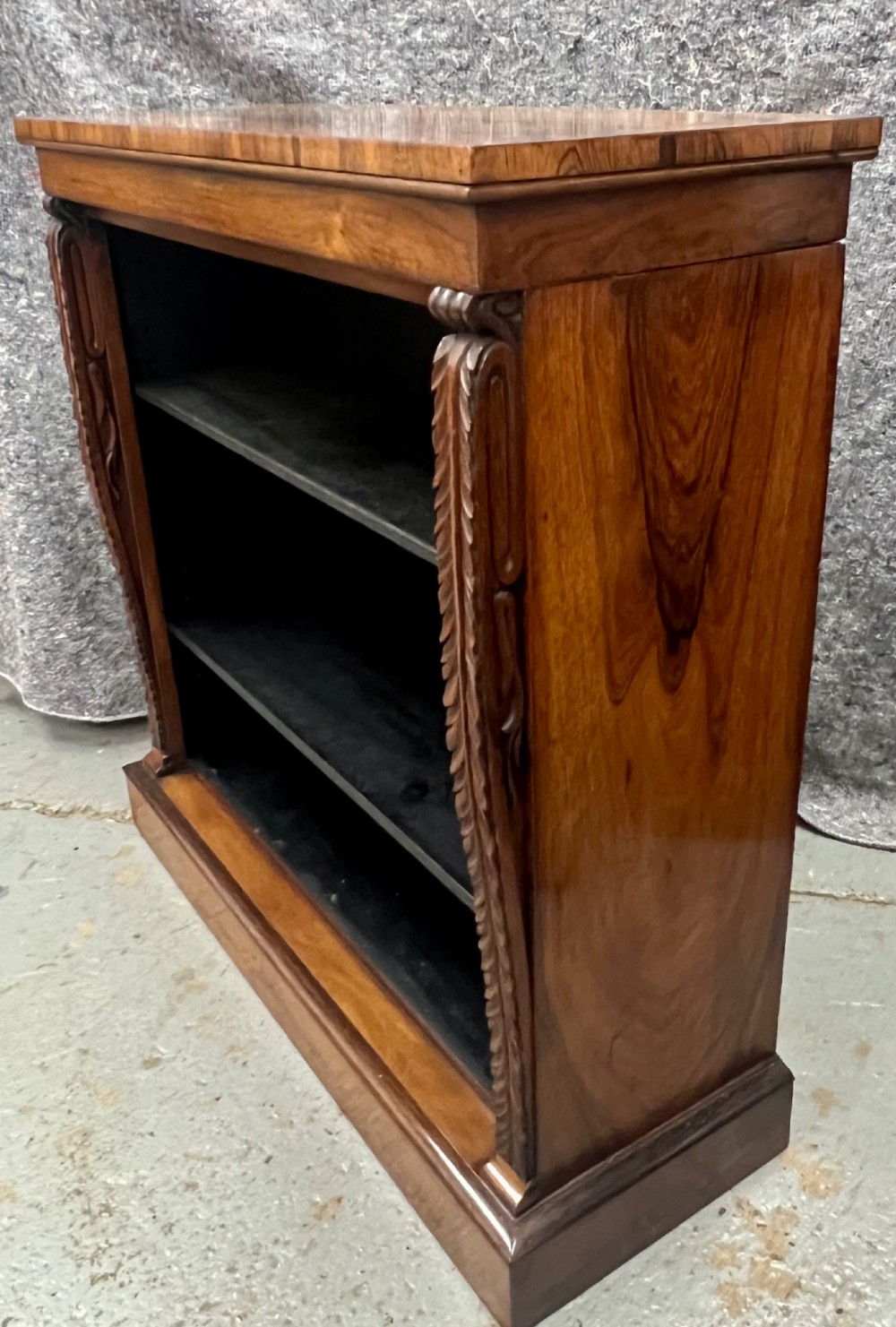 A low Regency open bookcase crafted from dark polished wood featuring carved twist mouldings on the side columns and three open shelves above a solid plinth base. View II