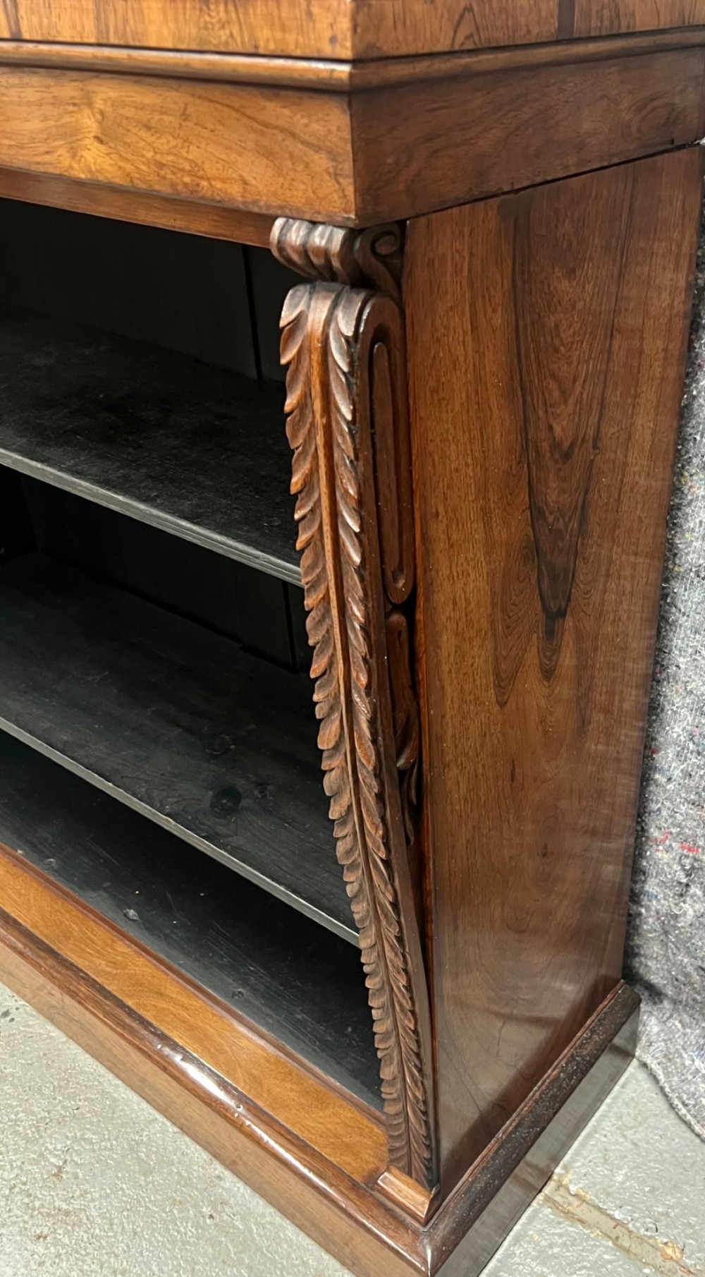 A low Regency open bookcase crafted from dark polished wood featuring carved twist mouldings on the side columns and three open shelves above a solid plinth base. View V
