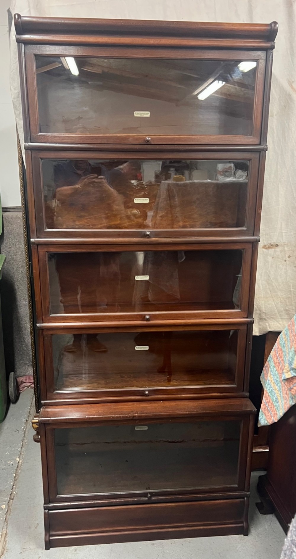 A five-tier dark mahogany Globe Wernicke stacking bookcase with glazed lift-up doors and maker labels.