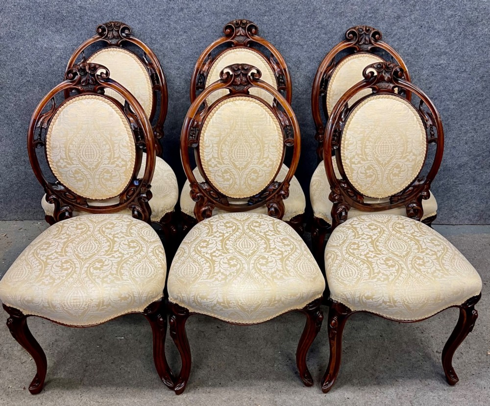 A set of six Victorian carved walnut dining chairs featuring oval balloon backs, cream patterned damask upholstery, and cabriole legs. View II