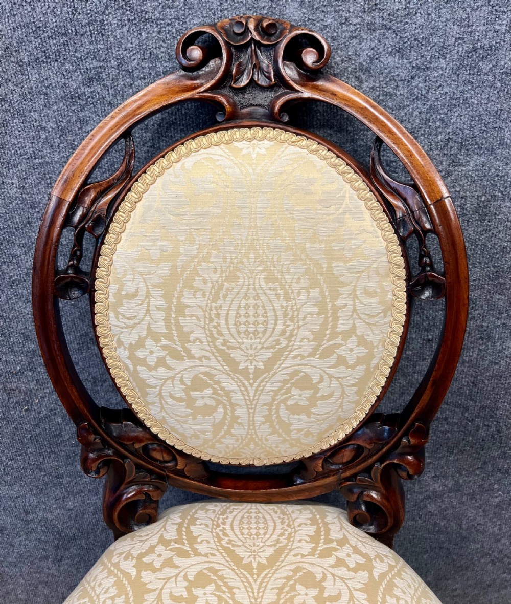 A set of six Victorian carved walnut dining chairs featuring oval balloon backs, cream patterned damask upholstery, and cabriole legs. View III