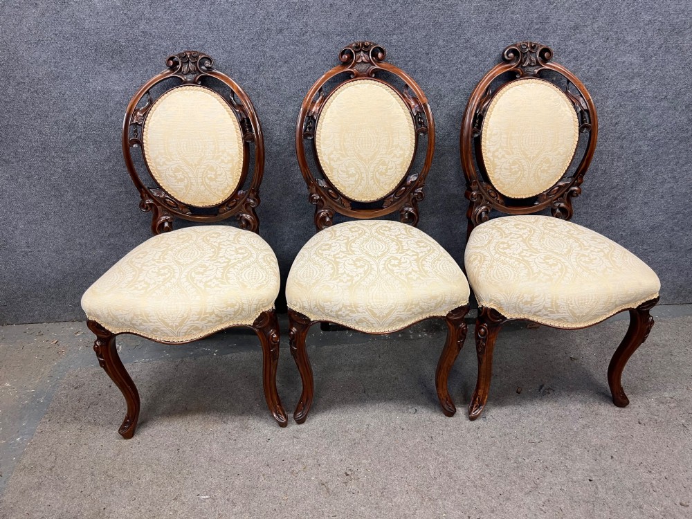 A set of six Victorian carved walnut dining chairs featuring oval balloon backs, cream patterned damask upholstery, and cabriole legs. View XI